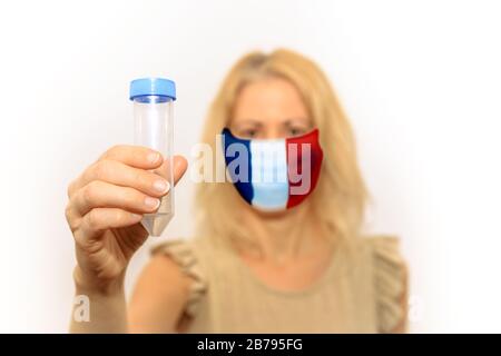 Donna con maschera facciale con bandiera francese che contiene una provetta. Concetto di focolaio e quarantena per l'infezione del coronavirus in Francia. Test antivirus Foto Stock