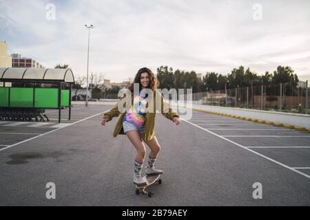 Inquadratura grandangolare di una ragazza su uno skateboard in una città Foto Stock