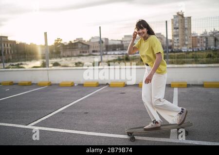 Inquadratura grandangolare di una ragazza su uno skateboard in un parco Foto Stock