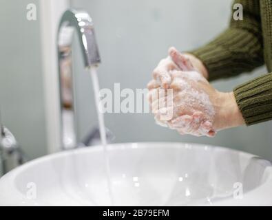 Donna lavando le mani con acqua e sapone in bagno closeup Foto Stock