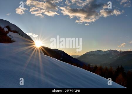 Vista della Valtellina da Campelli. Il sole sta scendendo dietro le montagne, riflettendo sulla neve fresca Foto Stock