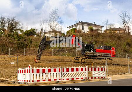 Escavatore in un cantiere. Costruzione di case. Attrezzature per costruzioni pesanti. Sviluppo urbano. Cantiere vuoto. Un veicolo sui montanti della catena. Foto Stock