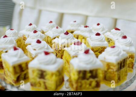 torte di spagna quadrate gialle con cioccolato e glassa con frutti di bosco in cima Foto Stock