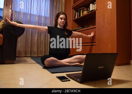 Torino, Italia. 14 Marzo 2020. Torino, ITALIA - 14 marzo 2020: Una ragazza segue da casa una lezione di yoga online. Il governo italiano ha imposto restrizioni senza precedenti per fermare la diffusione dell'epidemia di coronavirus COVID-19, tra le altre misure i movimenti delle persone sono autorizzati solo per il lavoro, per l'acquisto di beni essenziali e per motivi di salute. (Foto Di Nicolò Campo/Sipa Usa) Credit: Sipa Usa/Alamy Live News Foto Stock