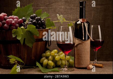 Ancora vita con bottiglie di vino, bicchieri e uva Foto Stock