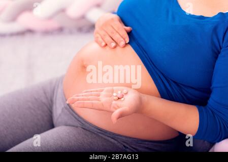 Vitamine durante la gravidanza. Donna incinta che tiene le pillole in mano ed espone il suo ventre. Foto Stock