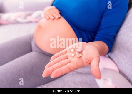 Vitamine durante la gravidanza. Donna incinta che tiene le pillole in mano ed espone il suo ventre. Foto Stock