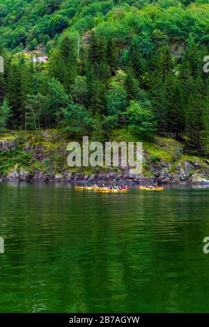 Persone che pagaiano le canoe a braccio stretto di Nærøyfjord - popolare destinazione turistica a Gudvangen dove il fiume Nærøydalselvi si svuota nel fiordo. Foto Stock