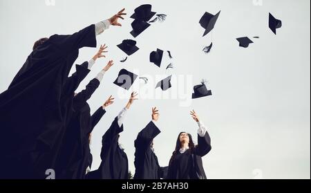 Un gruppo di laureati getta i cappelli nel cielo. Foto Stock