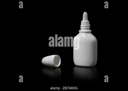 Flacone di liquido bianco con tappo su sfondo nero, vista laterale ravvicinata. Foto Stock