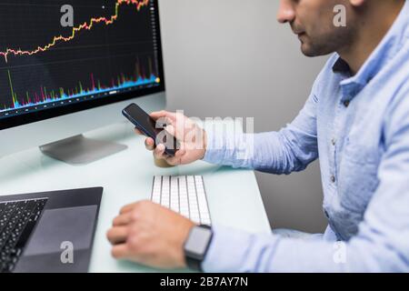 Imprenditori stock trading online. Stock broker guardando i grafici, indici e numeri su più schermi di computer. I colleghi che sono in discussione trad Foto Stock