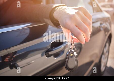 L'uomo in macchina ha messo la mano fuori e tiene le chiavi. Primo piano. Foto Stock