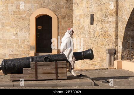 Una donna anziana medita e guarda in lontananza mentre siede su un cannone medievale. 2020.03.01. Odessa. Ucraina Foto Stock
