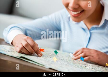 Discesa africana donna tour agente seduto al tavolo in ufficio, attaccare bandiere sulla mappa posti sorridenti allegri primo piano Foto Stock