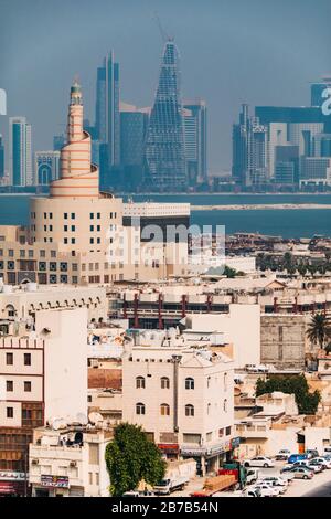 La famosa moschea a spirale del Kassem Darwish Fakhroo Islamic Center vicino a Souq Waqif a Doha, Qatar. Lo skyline della città può essere visto dietro nella foschia Foto Stock