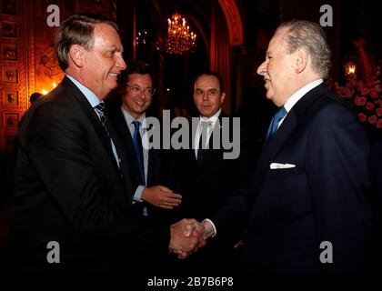 Il presidente brasiliano Jair Bolsonaro, a sinistra, saluta i membri della delegazione mentre il suo segretario alla stampa Fabio Wajngarten, 2° a sinistra, guarda al resort Mar a Lago 7 marzo 2020 a Palm Beach, Florida. Fabio Wajngarten si è testato positivo per il coronavirus COVID-19 poco dopo la cena a Mar-a-Lago. Foto Stock