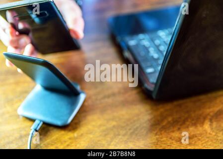 Lo smartphone per la ricarica MAN utilizza un supporto di ricarica wireless in ufficio Foto Stock