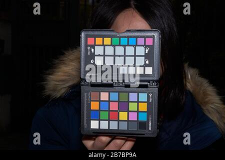 Donna in possesso di passaporto X-rite colorchecker sul posto per fotocamera bilanciamento del bianco e foto di calibrazione del colore Foto Stock