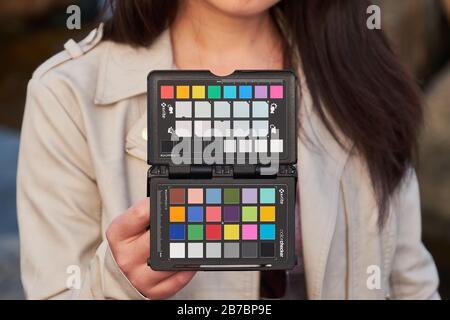 Donna in possesso di passaporto X-rite colorchecker sul posto per fotocamera bilanciamento del bianco e foto di calibrazione del colore Foto Stock