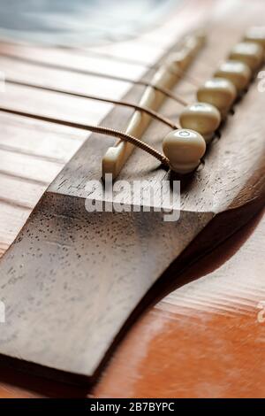 Sella a ponte con strings close-up, su una vecchia chitarra acustica. Foto Stock