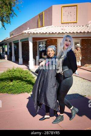 Un trendy hair stylist da Lady and Wolf Hair Salon ride & Walks con il suo cliente affumicato con cuffia doccia coperta capelli bagnati nella città vecchia Scottsdale, Arizona Foto Stock