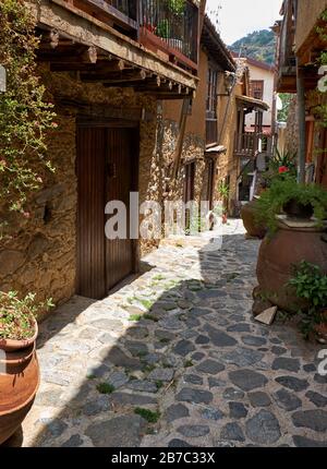 La vista della stretta strada lastricata in pietra della vecchia Kakopetria fiancheggiata da fiori nei vasi. Distretto di Nicosia. Cipro Foto Stock