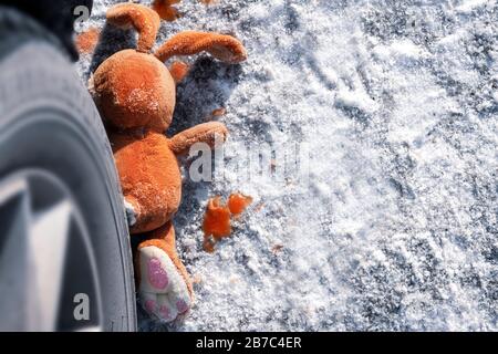 Incidente per bambini su una strada invernale, coniglio giocattolo. Morte sulla strada, incuria e pericolo. Attenzione e cautela. Roadkill inverno, sangue su s. Foto Stock