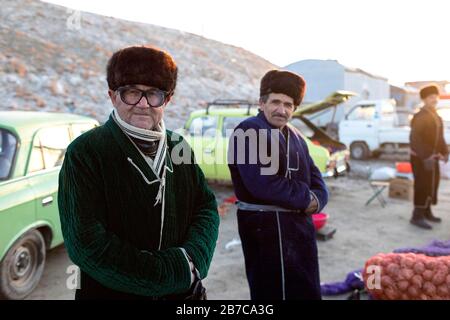 Uomini locali che indossano cappelli di pelliccia e grande glassare sul mercato del bestiame mattina in un villaggio vicino a Bukhara, Uzbekistan Foto Stock