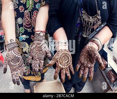 Donna turistica che li mostra mani con tradizionale henné pittura mehendi alla strada principale bazar a Delhi Foto Stock