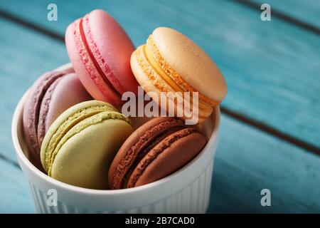 I biscotti di maccheroni sono posti in un piatto bianco su uno sfondo di legno blu. Foto Stock