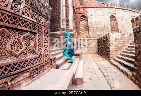 Donna in verde vestito indiano con sciarpa all'antico complesso Qutub Minar a Delhi, India Foto Stock