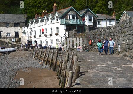 Persone a piedi sul Muro del Porto vicino al Red Lion Hotel nel villaggio di pescatori di Clovelly sulla South West Coast Path, North Devon. Inghilterra, Regno Unito. Foto Stock