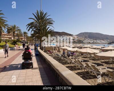 Passeggiata sul lungomare a Playa de las Vistas a Los Cristianos, Tenerife, Isole Canarie Spagna, in una calda giornata di sole Foto Stock