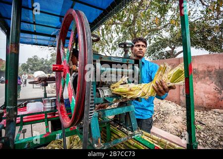 Agra, UTTAR PRADESH, INDIA - FEBBRAIO 24, 2015: Giovane indiano che fa succo di canna da zucchero che è molto famoso in India Foto Stock