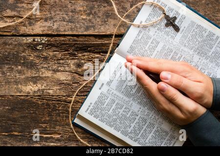 L'uomo legge una preghiera dalla Bibbia su sfondo ligneo con spazio per il testo Foto Stock