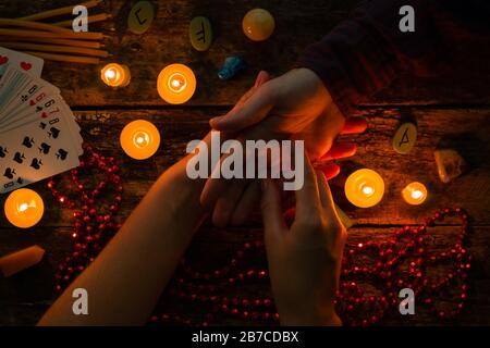 fortuneteller legge fortune a mano su uno sfondo di candele e rune Foto Stock