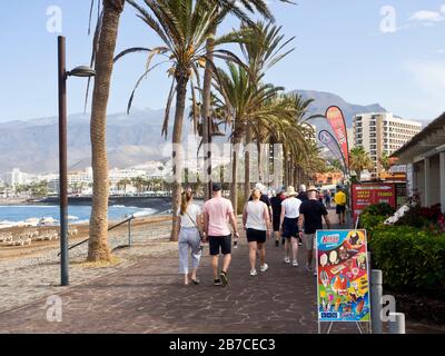 Una passeggiata mattutina lungo il lungomare di Playa de las Americas, Tenerife, Isole Canarie Spagna, un Teide frizzante in lontananza Foto Stock