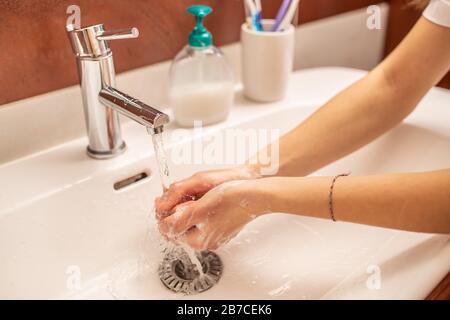 Lavare le mani con acqua e sapone liquido in bagno Foto Stock
