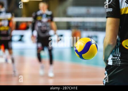 Pallavolo volare vicino al giocatore prima del servizio con campo da gioco in background. Foto Stock