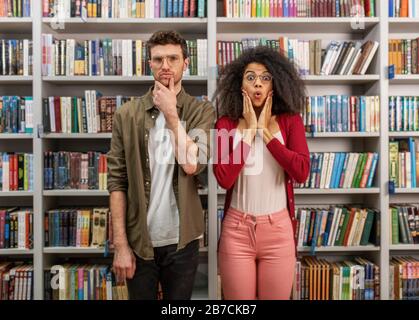 Giovane studente con espressione stupita in una biblioteca Foto Stock
