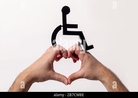 Segno disabile con la forma di mano del cuore di amore qui sotto. Concetto di cura per la disabilità su sfondo bianco. Foto Stock