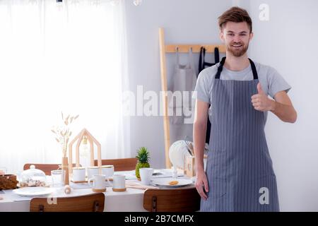 Ritratto di un maschio sorridente cook gesti segno visita in cucina. Foto Stock