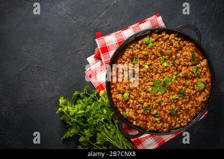 sause bolognese in piastra di ferro a tavola nera. Foto Stock