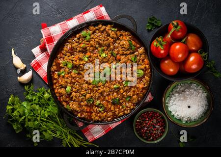 sause bolognese in piastra di ferro a tavola nera. Foto Stock