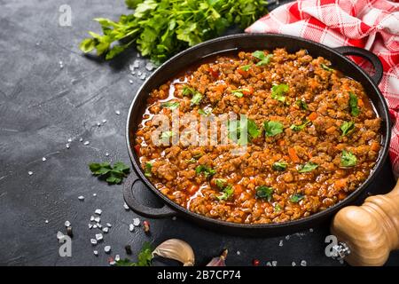 sause bolognese in piastra di ferro a tavola nera. Foto Stock