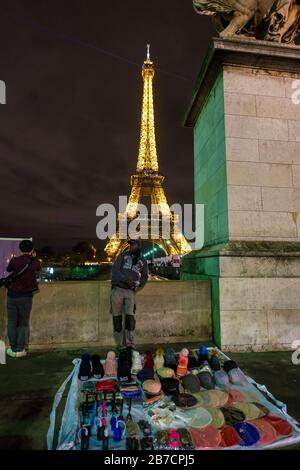 Uomo che vende merci per le strade di fronte alla Torre Eiffel a Parigi, Francia, Europa Foto Stock