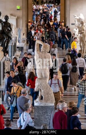 Vista posteriore della scultura in marmo di Diing Slave dell'artista rinascimentale italiano Michelangelo in una sala affollata al Museo del Louvre di Parigi, Francia, Europa Foto Stock