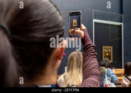 Tourist utilizza il suo smartphone per scattare foto della pittura della Monna Lisa dell'artista Leonardo da Vinci, Museo del Louvre, Parigi, Francia, Europa Foto Stock