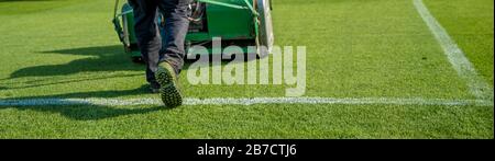 tagliare l'erba prima della partita sul campo di calcio con un trattore Foto Stock