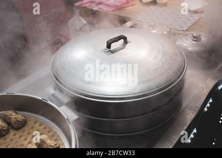 Hot Pot a vapore su Street Night Marker. Pressure Cooker e Steam in background. Foto Stock